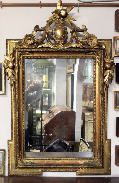 Specchiera di linea rettangolare in legno dorato con cimasa e decori laterali intagliati a motivi di fiori e foglie d&#39;acanto, altezza 120x78 cm, XIX secolo.