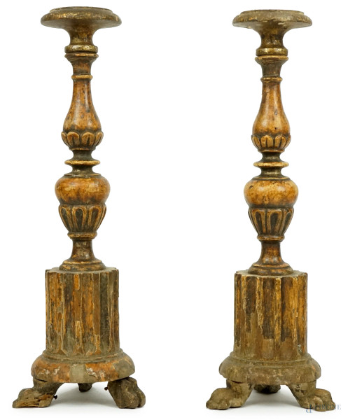 Coppia di antichi torcieri in legno intagliato e dorato, corpo a balaustro su base a mezza colonna scanalata, tre piedi leonini, cm h 36, (difetti).