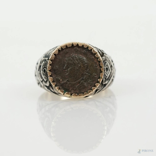 Anello da uomo in oro e argento con moneta incastonata, decori a rose e nastri intrecciati, XX se...