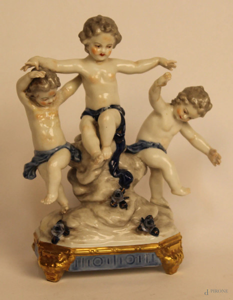 Gruppo in porcellana chiara a soggetto di bambinelli, particolari blu e dorati, h. 19 cm.