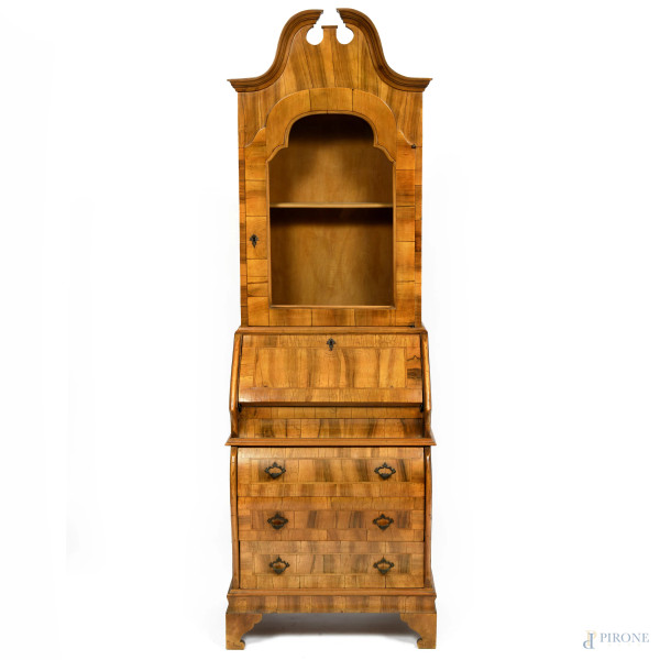 Trumeau in legno impiallacciato in varie essenze con corpo inferiore a fronte mosso a tre cassetti sormontati da sportello a ribalta. Corpo superiore a singola anta vetrata terminante in elemento apicale sagomato, XX secolo, cm 198x62x42, (segni di usura, scalfiture, difetti)