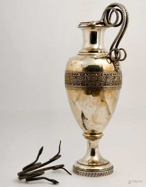 Grande vaso in metallo argentato con base circolare decorata ad incisione geometrica, al corpo centrale fascia cesellata a candelabre di ispirazione classica e mascheroni di fauno a rilievo. Anse serpentiformi. Altezza cm 58, (difetti - un'ansa necessita di saldatura)