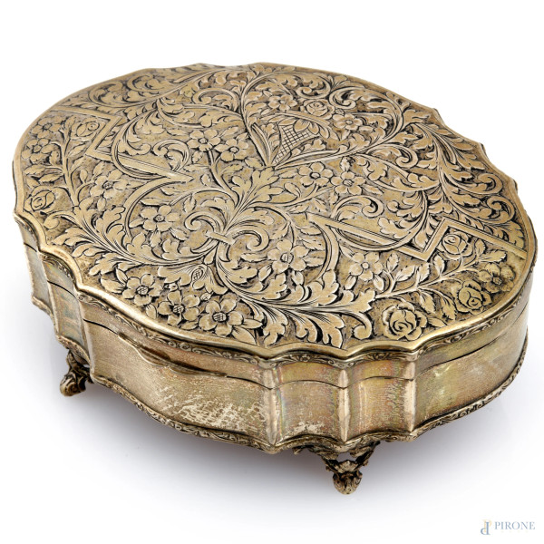 Cofanetto in argento dal profilo mistilineo poggiante su quattro piedini. Coperchio cesellato a motivi vegetali. Interno con imbottitura in velluto. Fondo in cartone. XX secolo, peso lordo gr 200, cm 5x13,5x10, (segni di usura, difetti)