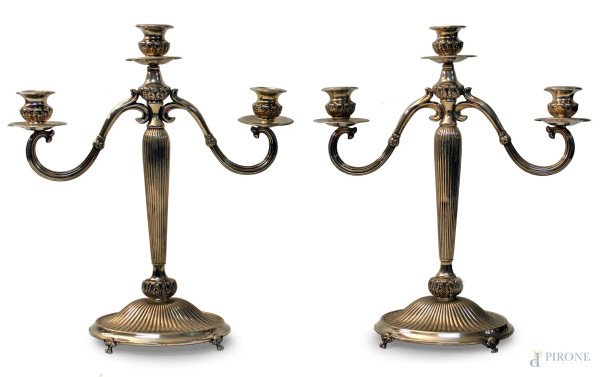Coppia candelieri a tre luci in argento baccellato, poggiante su quattro piedini, H 35 cm, gr. 1350.