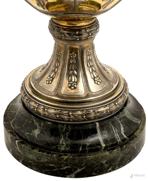 Grande vaso biansato in argento con prese a guisa di putti su foglie d'acanto a sorreggere l'orlo...