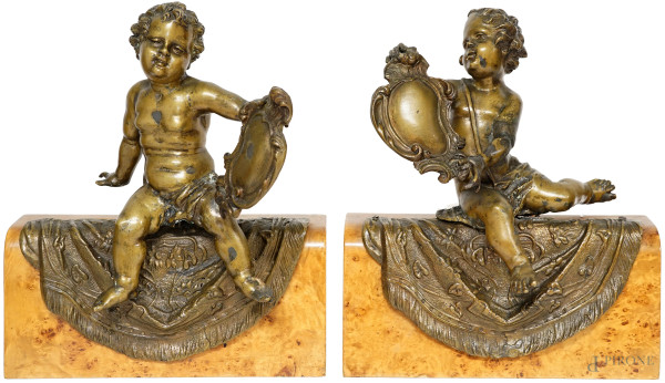 Coppia di putti in bronzo, fine XIX secolo, raffigurati nell'atto di mostrare uno scudetto, montati su basi in legno, cm h 39x33x10, (difetti e restauri)