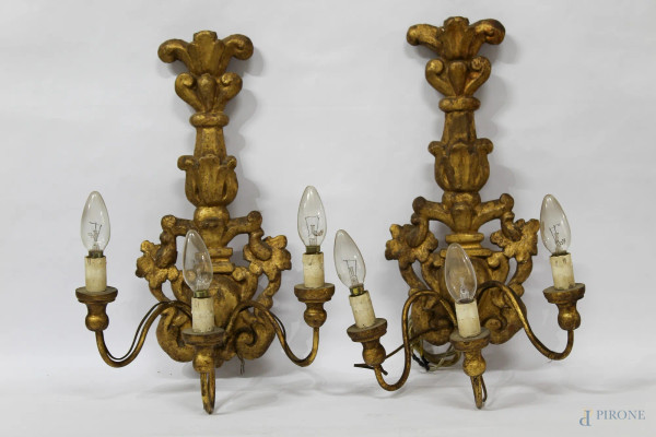 Coppia di appliques a tre luci, in legno intagliato e dorato, XIX sec., H 44 cm.