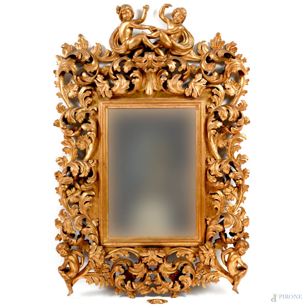Specchiera con cornice in legno dorato e intagliato a volute fogliacee con putti agli angoli inferiori e alla sommità, XX secolo, cm 140x95, (difetti)