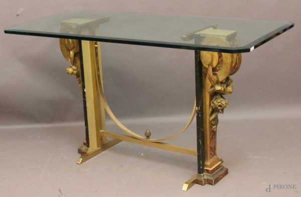 Tavolo in cristallo poggiante su due capitelli in legno dorato e laccato, base in ottone, h. 78x140x75 cm.