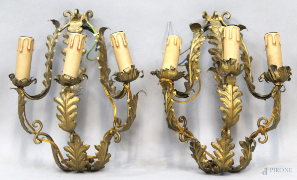 Coppia di appliques in metallo dorato a tre luci, braccia e portacandele a motivi fogliacei, cm h 33, XX secolo, (segni del tempo).