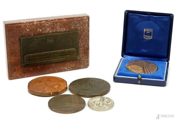 Lotto composto da un fermacarte con placca in metallo e cinque medaglie in materiali diversi, misure max cm 6, entro custodie, (difetti).