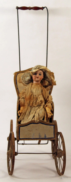 Antica bambola con testa in porcellana, completo di carrozzina.