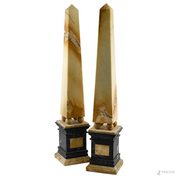 Coppia di obelischi in marmo giallo sorretti da quattro sfere poggianti su base in marmo nero e giallo, XX secolo, altezza complessiva cm 81, (scalfiture, segni di usura, difetti)