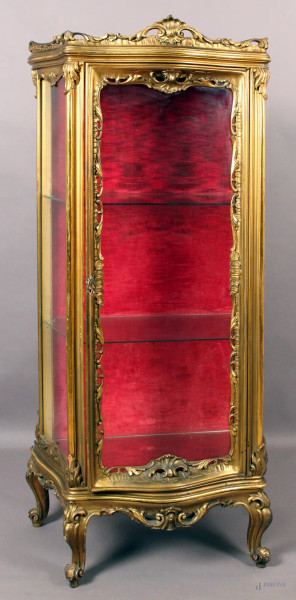 Vetrina di linea mossa in legno intagliato e dorato ad uno sportello, laterali in vetro, XX secolo, altezza 167x77x43 cm.
