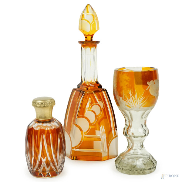 Un bottiglia da liquore, una bottiglia portaprofumo  ed un calice in cristallo arancio con decori a mola di volatili, alt.max cm 34, XX secolo.