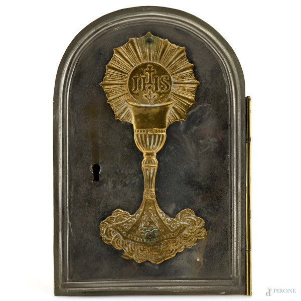 Reliquiario in metallo dorato e argentato con calice a rilievo e sportello centrale celante crocifisso in legno e metallo e ex voto, XX secolo, cm 23,5x16x5, (segni di usura, difetti)