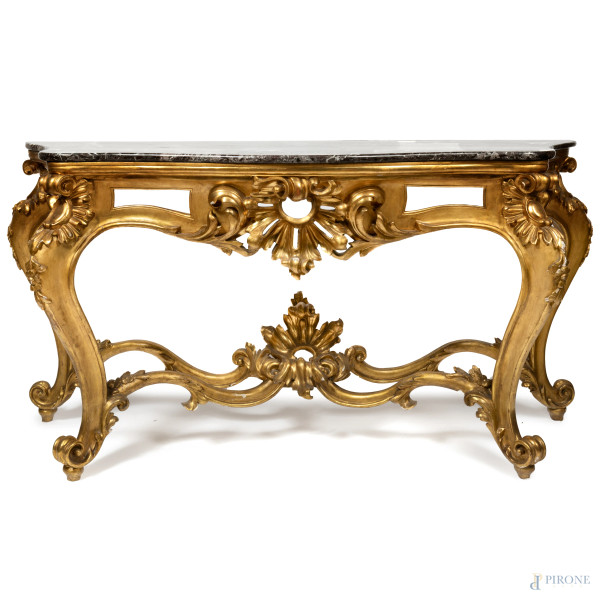 Consolle in legno dorato e intagliato con piano in marmo. Gambe mosse terminanti con piedi a ricciolo raccordate da quattro traverse mosse e elemento centrale a volute, XIX secolo secolo, cm 101x195x72, (scalfiture, scheggiatura al piano e cadute di doratura)