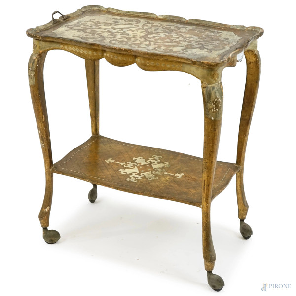 Tavolinetto in legno laccato e dorato, metà XX secolo,  a due ripiani con particolari incisi, quattro gambe mosse su rotelle, cm h 64x558,5x36, (difetti).