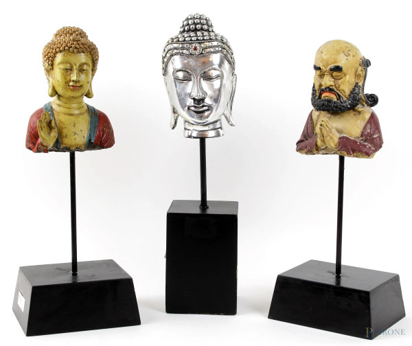 Lotto composto da due teste di Buddha e una testa di santone, in legno dipinto e resina, alt. max cm 10, epoche diverse, (difetti).