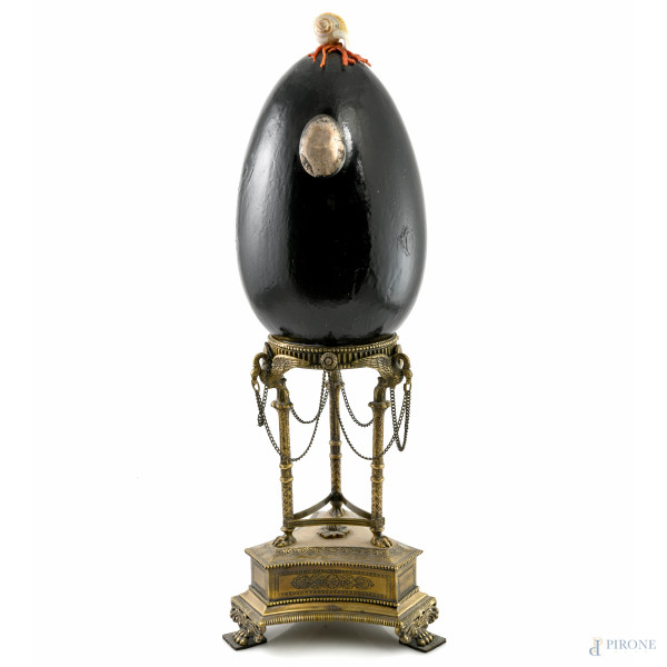 Scultura in resina dipinta a foggia di uovo di struzzo con applicazioni in conchiglia, finto corallo e argento 800/000, poggiante su base in struttura in bronzo dorato, XX secolo, altezza cm 52, (segni di usura, difetti, scalfiture)