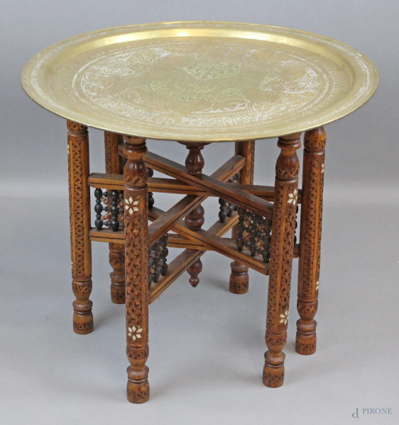 Tavolino da fumo orientale, con piatto in ottone inciso, base pieghevole in legno intagliato ed intarsiato in madreperla, altezza cm. 52, diametro cm.58, XX secolo.