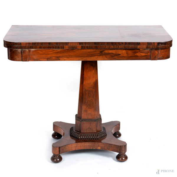 Tavolo da gioco in legno impiallacciato. Piano apribile celante vano su fusto poggiante su pedana sagomata, XX secolo, cm 74x97x48. (segni di usura, scalfiture, difetti)