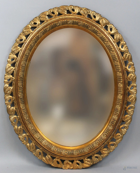 Specchiera di linea ovale in legno intagliato e dorato, XX secolo, cm 60x80