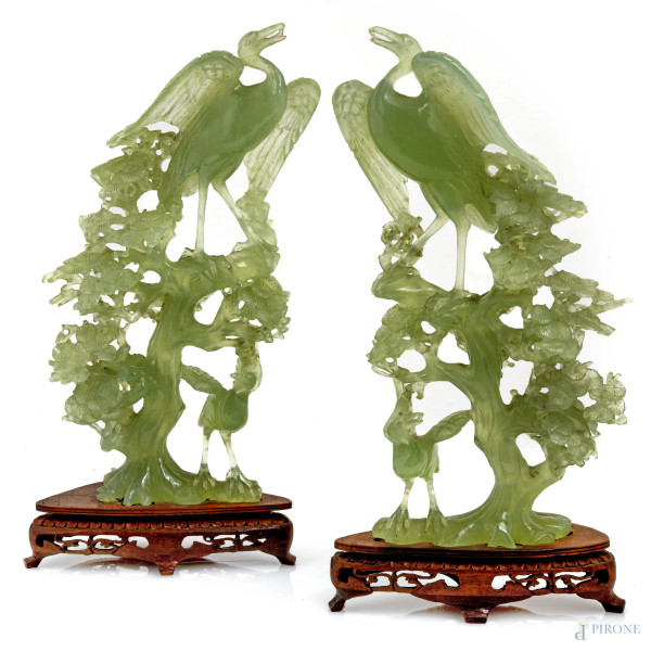 Lotto di due sculture in giada raffiguranti albero con aironi su basi in teak, XX secolo, altezza massima cm 34, (scalfiture, rotture)