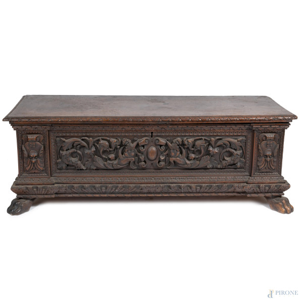 Cassapanca in noce intagliato a volute, mascheroni e stemmi, XIX secolo, cm 54x160x55, (segni di usura, scalfiture, rotture, difetti)
