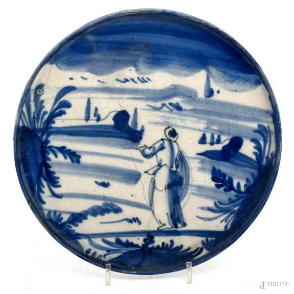Piatto in ceramica blu con figura in  un paesaggio, XX secolo, diametro cm 24,5, (felature, scalfiture, cadute di colore, difetti)