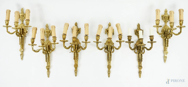Sei appliques a tre luci stile Luigi XVI in bronzo dorato, XX secolo, con tre bracci a doppia voluta e fusto architettonico sormontato da un vaso ad urna ornato da festoni, cm h 43,5