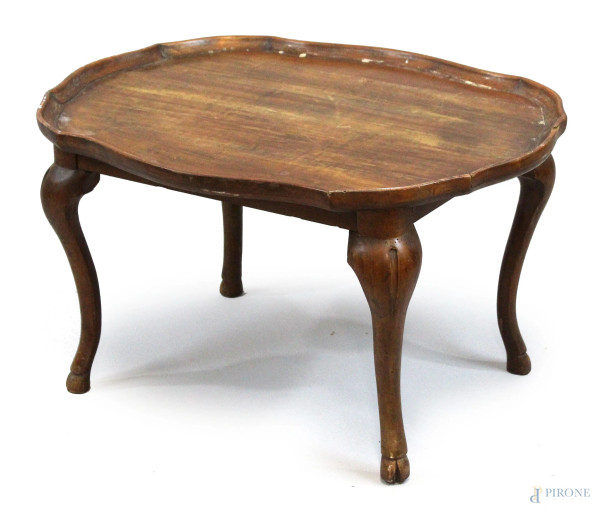 Basso tavolinetto in noce, XX secolo, piano di linea ovale sagomata, poggiante su quattro gambe mosse, cm h 44x59,5x77, (difetti).