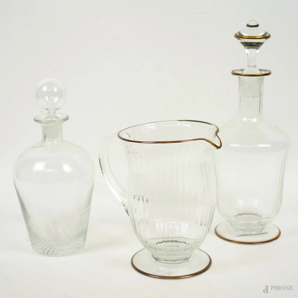 Lotto di due bottiglie ed una caraffa in vetro trasparente con finiture dorate, XX secolo, alt. max cm 32