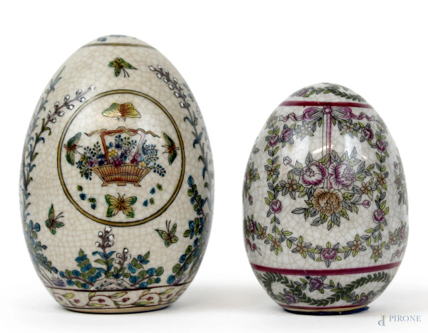 Lotto di due uova in ceramica, decori policromi a motivi floreali e di volatili, cm h 14, (segni del tempo).