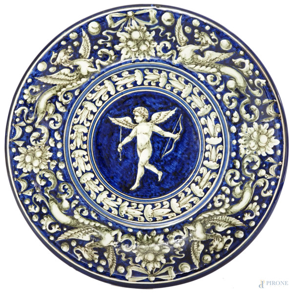 Piatto in maiolica bianca e blu con decori vegetali e un cupido, Chianciano, XX secolo, diametro cm 35