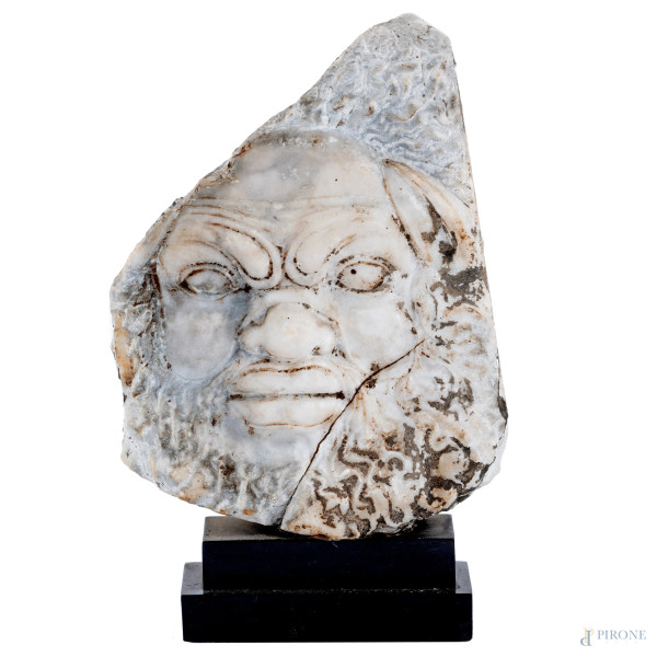 Frammento con bassorilievo di volto di fauno in marmo su base marmo, XX secolo, altezza cm 28, (segni di usura, rotture, scalfiture)