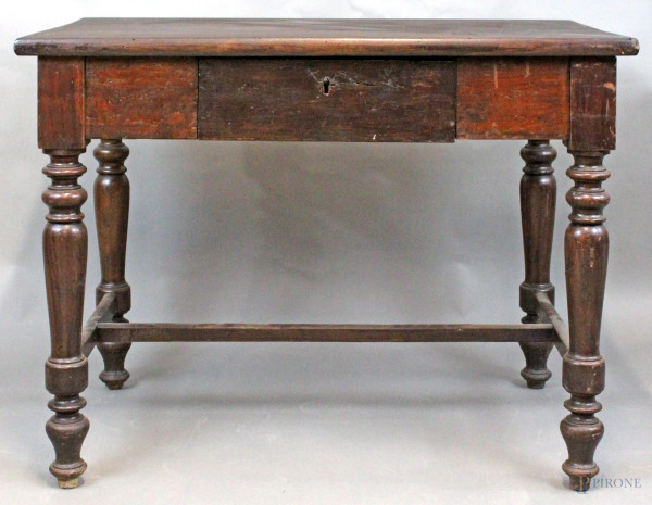 Tavolo scrittoio in legno tinto a noce ad un cassetto poggiante su quattro gambe tornite legate da traversa, cm h 77x99x60, prima metà XX secolo.