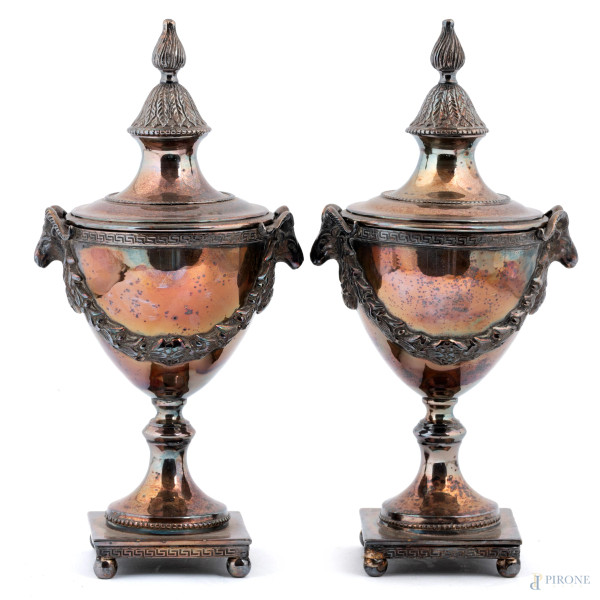 Coppia di potiche in metallo argentato con teste di montoni e festoni a rilievo, XX secolo, altezza cm 30, (segni di usura, difetti)