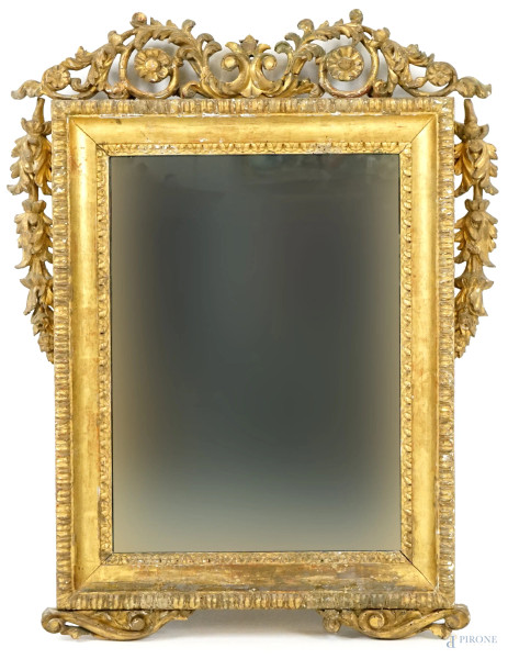 Specchiera in legno intagliato e dorato, XIX secolo, di linea rettangolare con cimasa scolpita a volute e fiori, festoni ricadenti ai lati, misure ingombro cm 86x66, luce cm 58x43, (difetti)