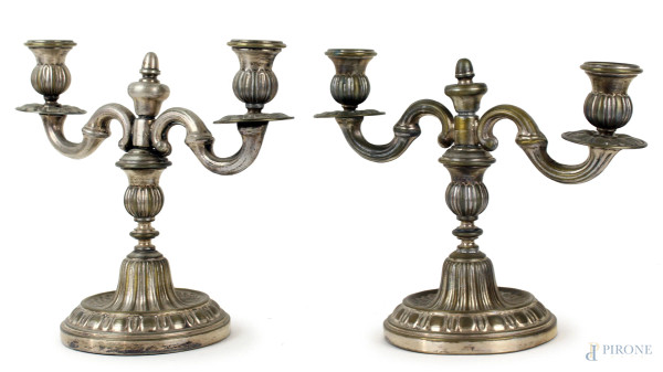 Coppia di candelabri in metallo argentato a due fiamme, braccia a volute, parti incise e sbalzate, cm 22,5x27,5x13, (segni del tempo)