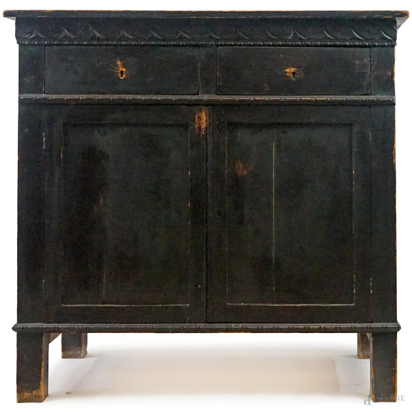 Credenza in legno ebanizzato, inizi XX secolo, piano rettangolare con fascia sottostante intagliata a meandro,  fronte a due cassetti e due sportelli, piedi dritti, cm h 101x105x52,5, (difetti)