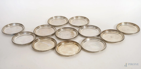 Dodici sottobicchieri in argento con profilo a perline, manifattura italiana, XX secolo, diametro cm 10, peso gr. 817