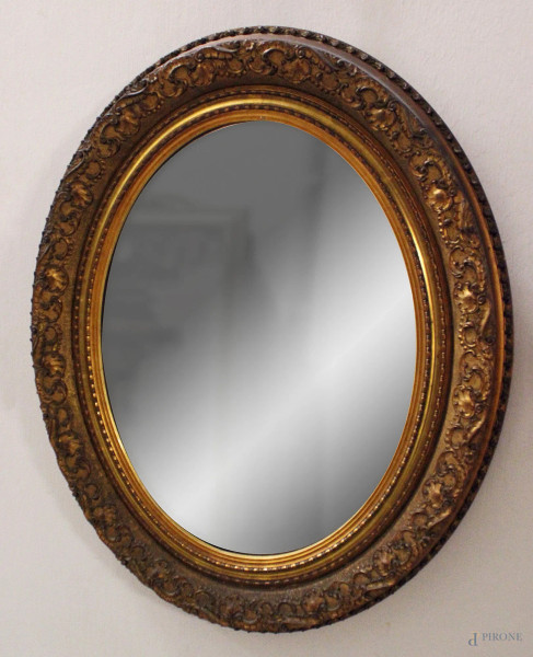Specchiera di linea ovale in legno intagliato e dorato, primi'900, h 70x50 cm.