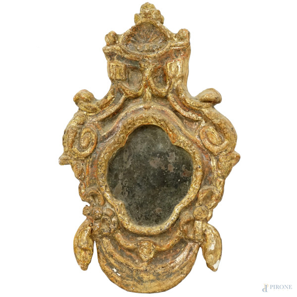 Antica specchiera in legno dorato e pastiglia, cimasa a conchiglia e cornice decorata a volute, nastri e fiocchi, luce quadrilobata, cm 51x32, (difetti)