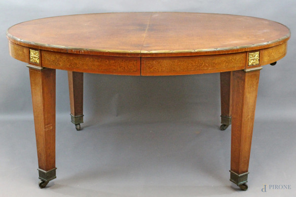 Tavolo di linea ovale impiallacciato in radica di thuja, poggiante su quattro gambe trocopiramidali, finiture in bronzo, completo di rotelle, cm h 78,5x156x129, XIX secolo, (difetti).