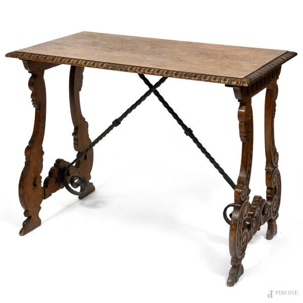 Piccolo tavolo stile fratino in noce intagliato, con gambe a lira raccordate al piano da traverse in ferro, XX secolo, cm 70x90x49, (segni di usura, scalfiture, difetti)
