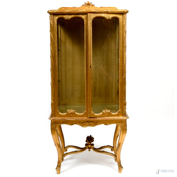 Vetrina a un'anta in legno scolpito e dorato con ricca decorazione a motivi floreali e vegetali. Piedi mossi, cimasa e angoli con intagli a rilievo. XX secolo, cm 154x69x38, (difetti)