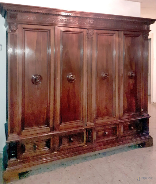 Armadio in stile Rinascimento, in legno tinto a noce, a quattro ante e quattro cassetti, particolari intagliati, altezza cm. 219x246x63, inizi XX secolo.