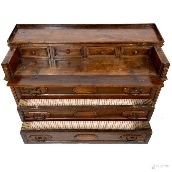 Cassettone in noce con fronte scandito da tre cassetti e finto cassetto. Piano superiore apribile...