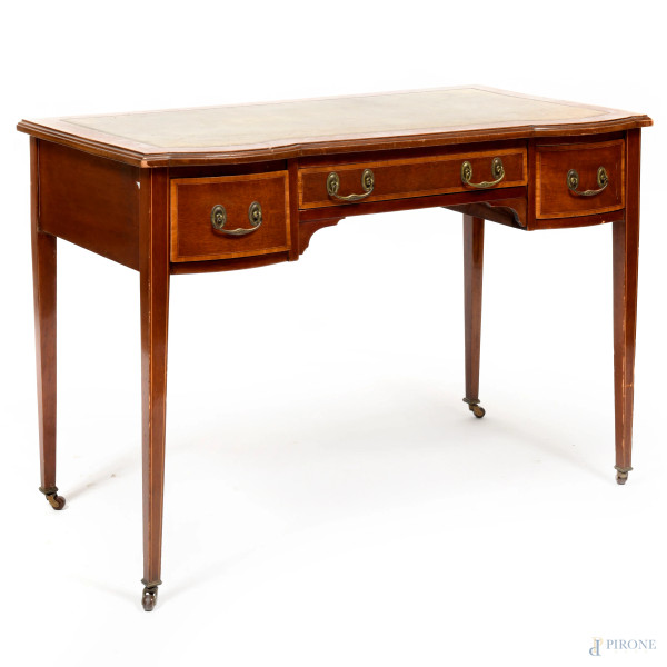 Scrittoio impiallacciato in varie essenze a tre cassetti con piano rivestito in cuoio verde con decori oro. Gambe munite di rotelle. XX secolo, cm 72x98x54, (segni di usura, scalfiture, graffi)